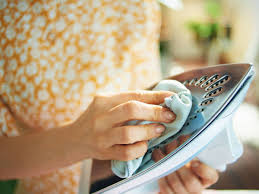 Demostrando cómo limpiar la suela de la plancha con un paño